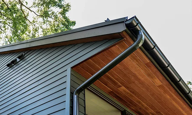 seamless-gutter-installation-solutions-central-mass.webp" alt="Modern dark seamless gutter system securely installed on a home exterior in Central Mass